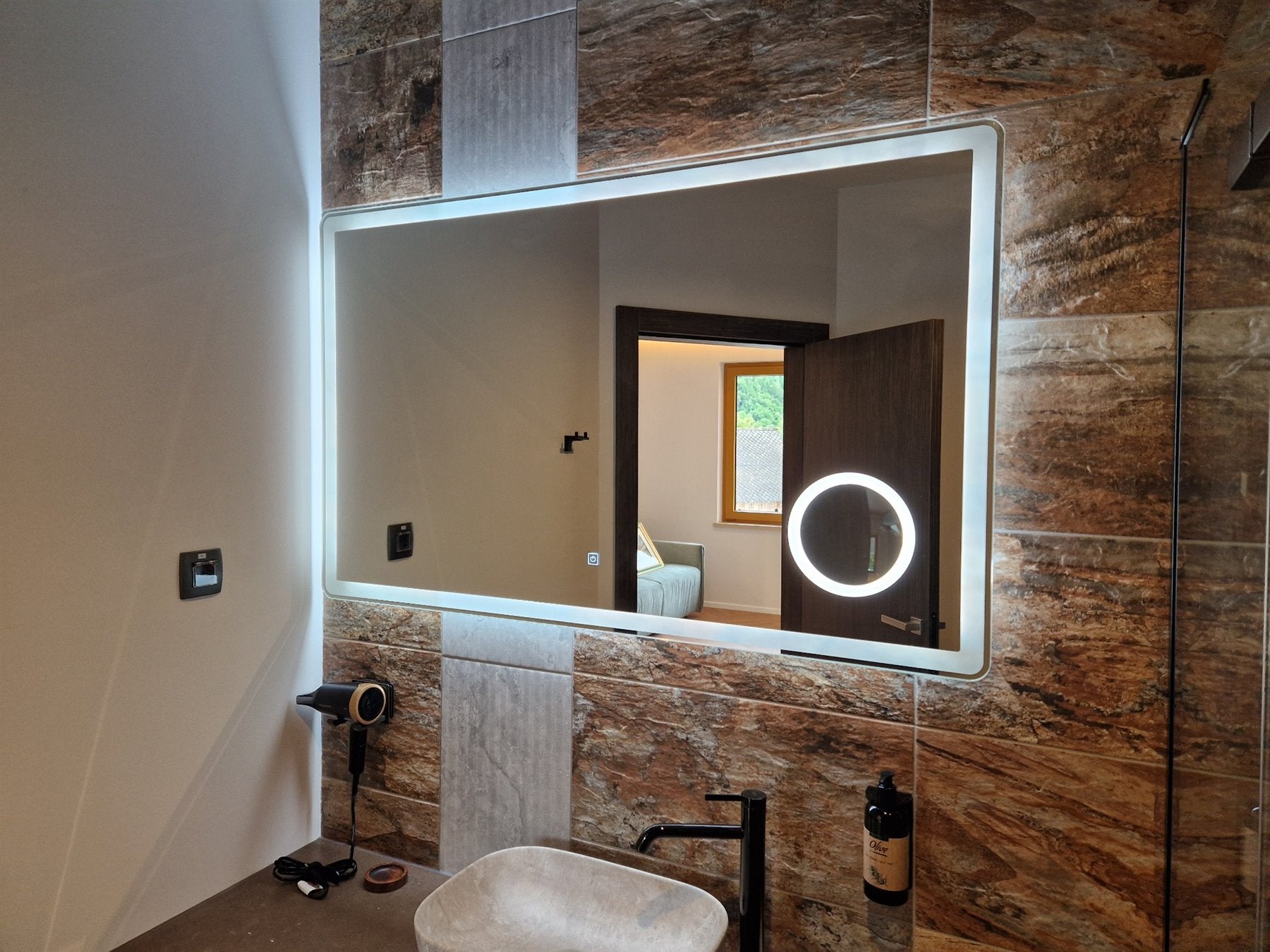 Rectangular LED mirror with a magnifier above the washbasin in a bathroom.