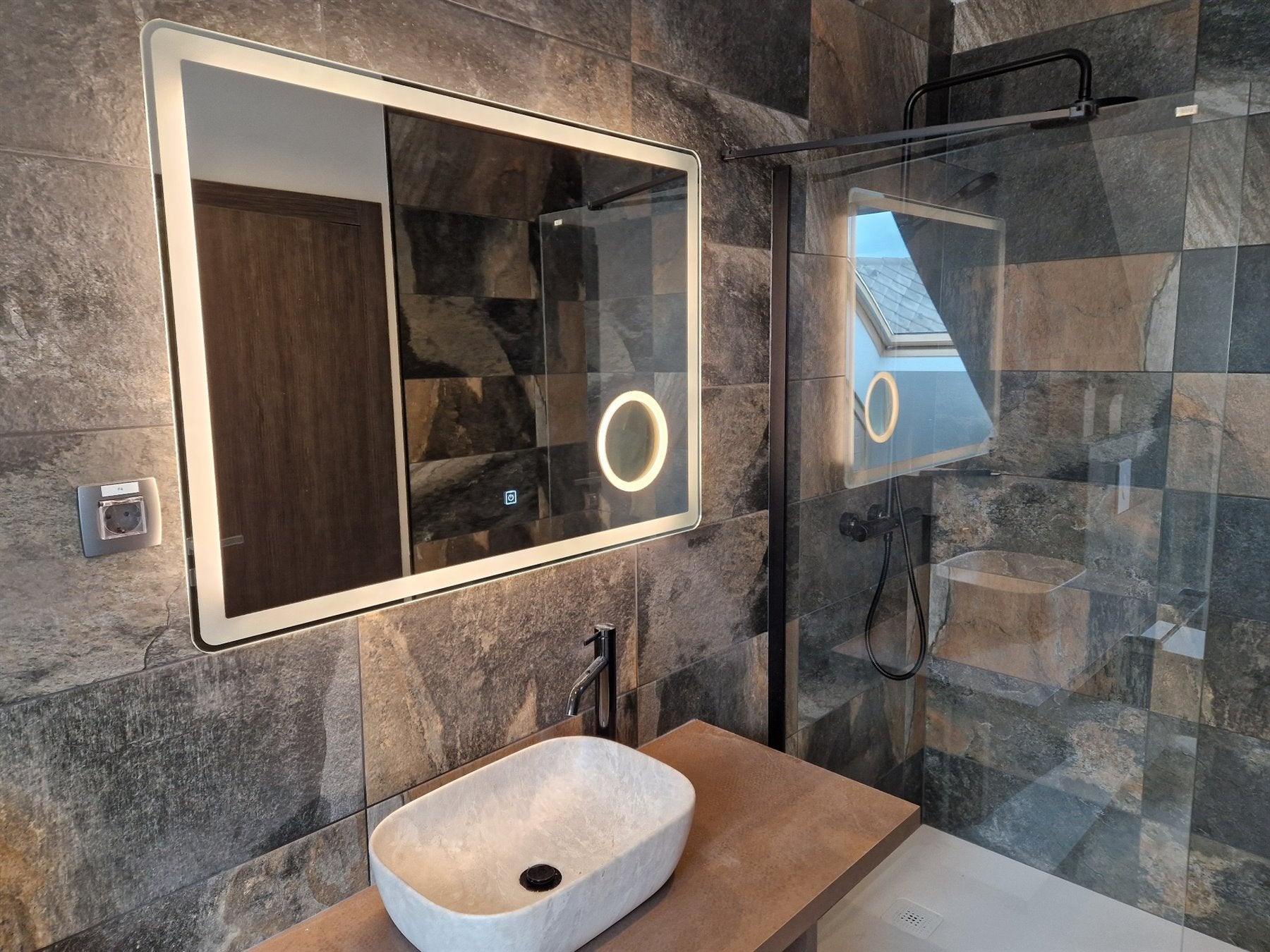 Rectangular LED mirror with a magnifier above the washbasin in a bathroom at Hotel Julijske Alpe.