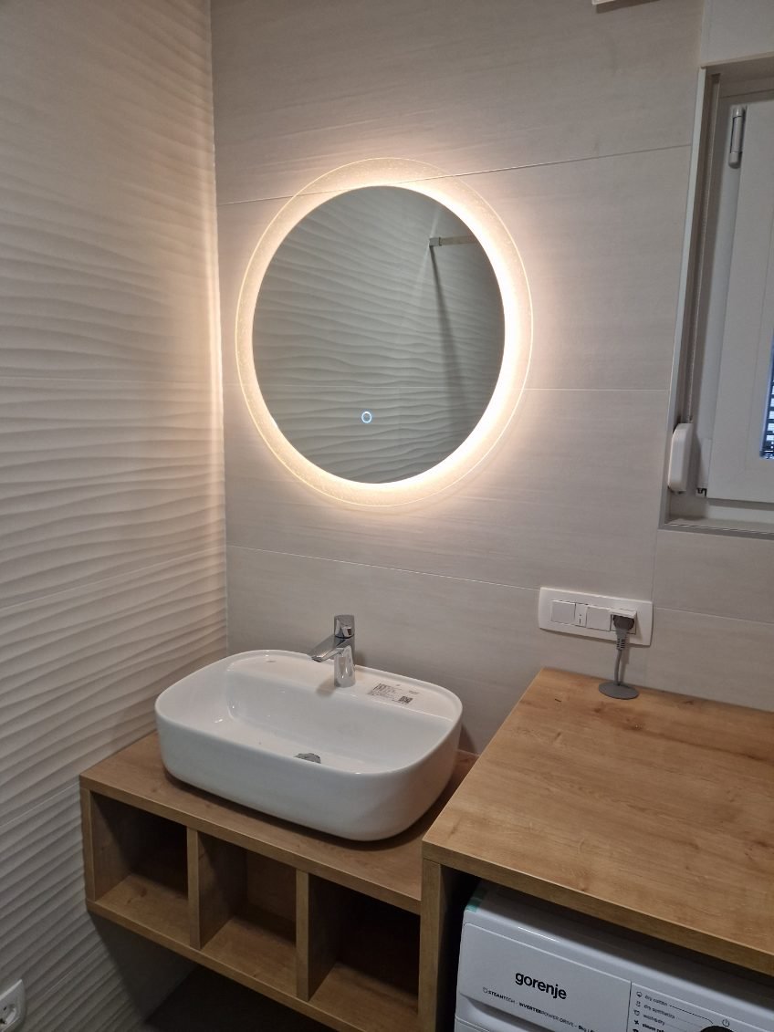 Round LED mirror above the washbasin in a bathroom.